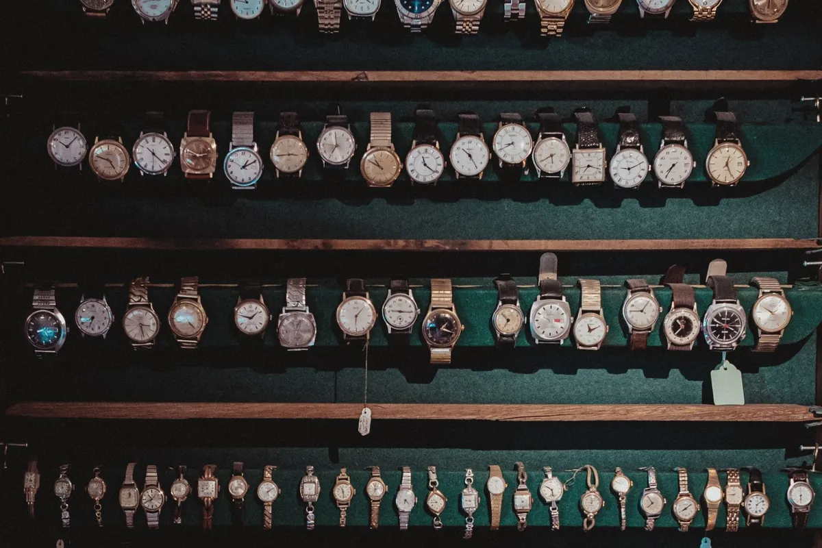 A diverse collection of vintage wristwatches displayed on dark wooden shelves, highlighting luxury timepieces.